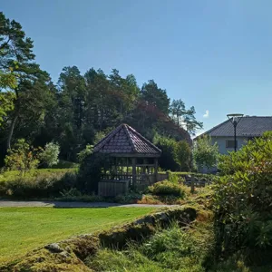 Et hus med en gresshage og trær rundt den